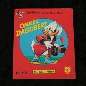 Peut inclure: Une couverture de livre rouge et bleue avec le titre "Oncle Picsou" et une image de bande dessinée de Picsou. Le livre est un Walt Disney's Micky Maus Buch, numéro 104, publié par Pestalozzi-Verlag.