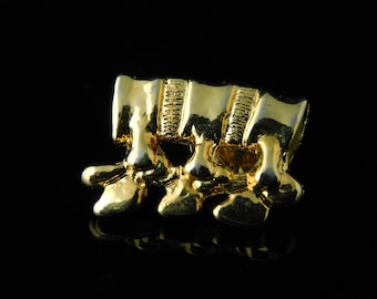 Puede incluir: Encanto de metal dorado en forma de vértebra humana. El encanto está detallado con crestas y surcos.