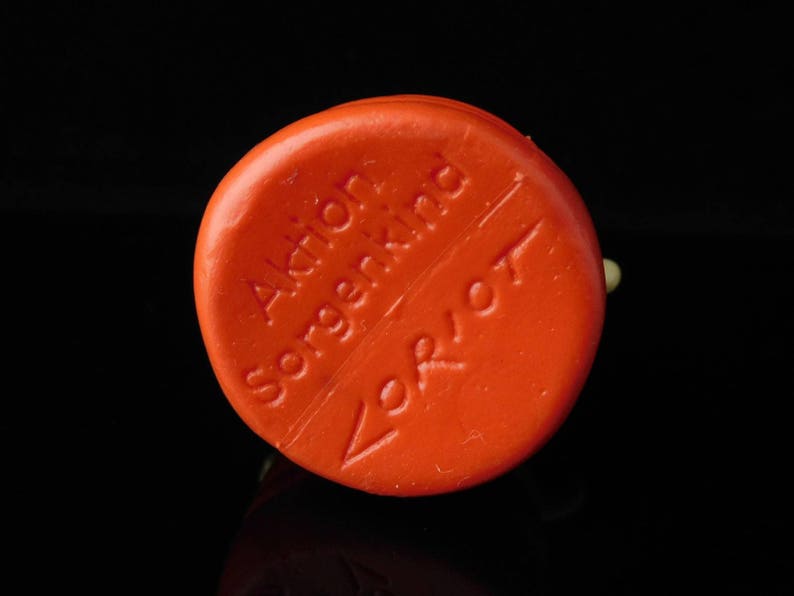 May include: Orange round soap bar with the text "Aktien Sorgenkind" and "Verbot" on it.