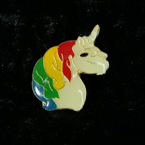 Könnte beinhalten: Eine weiße Einhornkopfnadel mit einer Regenbogenmähne. Die Mähne ist rot, gelb, grün und blau.