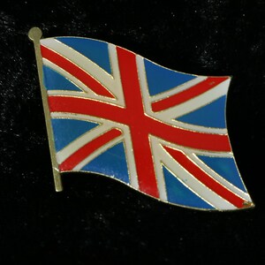 Könnte beinhalten: Eine Anstecknadel mit dem Union Jack, der Nationalflagge des Vereinigten Königreichs. Die Anstecknadel hat einen goldfarbenen Rand und ein wehendes Flaggenmuster mit roter, weißer und blauer Emaille. Die Flagge ist an einem goldfarbenen Mast befestigt.