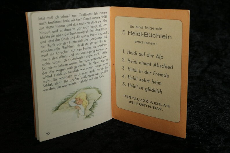 Puede incluir: Una portada de libro vintage con una imagen de una ni&ntilde;a durmiendo en una cama. La portada del libro es naranja y blanca y tiene el texto "5 Heidi-B&uuml;chlein erschienen" impreso en ella. El texto debajo de la imagen dice "PESTALOZZI-VERLAG 851 F&Uuml;RTH/BAY."