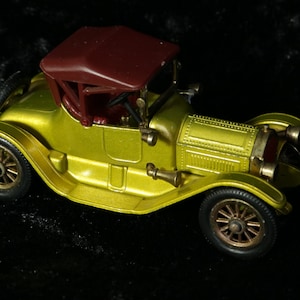 Puede incluir: Un coche de juguete amarillo con un techo marrón. El coche tiene un diseño detallado y es de estilo vintage.