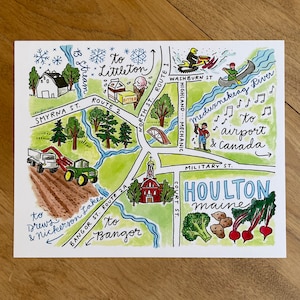 May include: A hand-drawn map of Houlton, Maine, with a blue, green, and red color scheme. The map shows the location of the airport, the Meduxnekeag River, and the town's main streets. The map also includes illustrations of a tractor, a church, a snowmobile, a canoe, and a farm stand with vegetables.