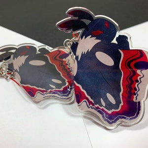 May include: Two clear acrylic charms featuring a black and white moth with red and purple accents. The moth has a skull-like face and large, black wings.