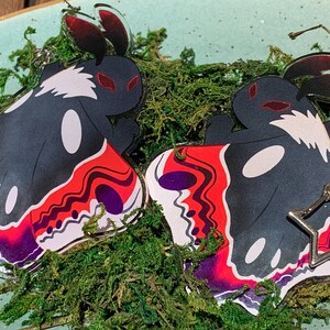May include: Two black and white butterfly-shaped acrylic charms with red, purple, and white marbled wings. Each charm has a silver star-shaped keychain attached.