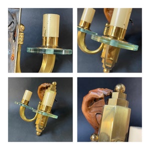 May include: Vintage brass wall sconces. Each sconce has a cylindrical light fixture, a clear glass disc, and a curved brass arm. The sconces have a warm glow and are ideal for adding a touch of vintage charm to any room. The sconces are approximately 20 cm in height.