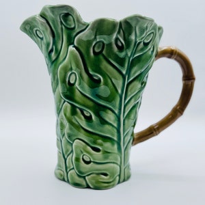 May include: A green ceramic pitcher with a bamboo handle. The pitcher is decorated with a leaf design.
