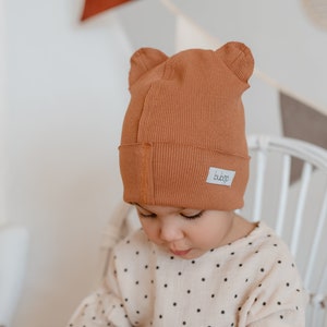 May include: A brown ribbed knit beanie with bear ears and a small white label that says "b.b.b.o."