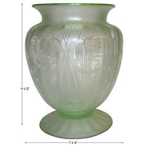 May include: A frosted green glass vase with an etched floral design. The vase is 9 1/2 inches tall and 7 1/4 inches wide.