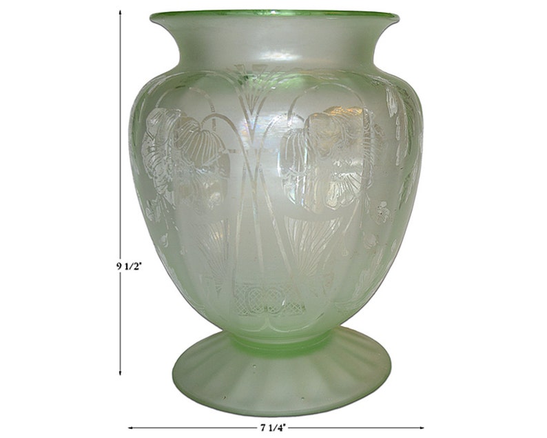 May include: A frosted green glass vase with an etched floral design. The vase is 9 1/2 inches tall and 7 1/4 inches wide.