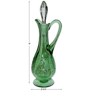 May include: A green glass pitcher with an etched floral design and a clear glass stopper. The pitcher is 9 inches tall and has a 2 3/4 inch base.