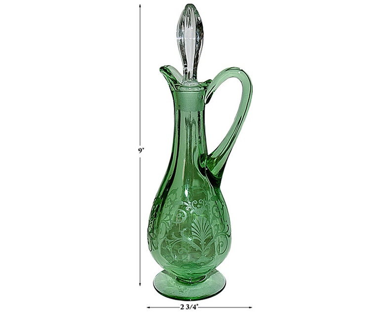 May include: A green glass pitcher with an etched floral design and a clear glass stopper. The pitcher is 9 inches tall and has a 2 3/4 inch base.