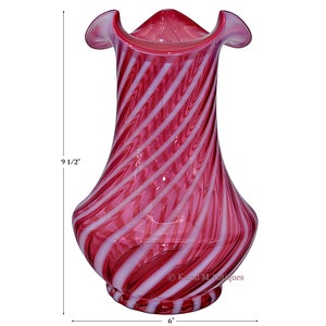 May include: A red and white swirl glass vase with a ruffled top. The vase is 9 1/2 inches tall and 6 inches wide.