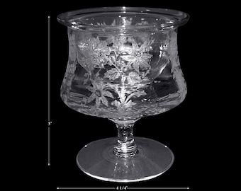 May include: A clear glass goblet with a floral etched design. The goblet has a wide bowl and a tall stem with a round base. It measures 5 inches tall and 4 1/4 inches wide.