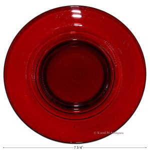 May include: A deep red glass plate with a raised center, measuring 7 3/4 inches in diameter.