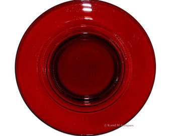 May include: A deep red glass plate with a raised center, measuring 7 3/4 inches in diameter.