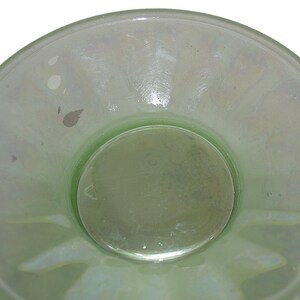 May include: A light green glass bowl with a scalloped edge and a smooth, slightly iridescent surface. The bowl has a smaller, circular bowl in the center.