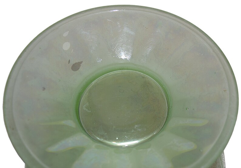 May include: A light green glass bowl with a scalloped edge and a smooth, slightly iridescent surface. The bowl has a smaller, circular bowl in the center.
