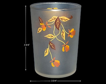 May include: A frosted glass tumbler with a floral design. The design features brown and yellow leaves and orange flowers. The tumbler is 3 3/4 inches tall and 2 3/4 inches wide.