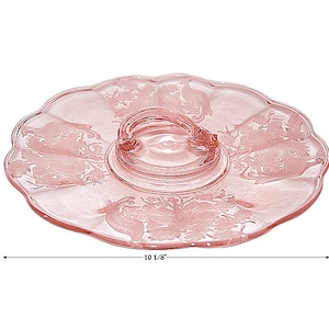 May include: A pink glass serving tray with a scalloped edge and a raised center with a handle. The tray is 10 1/8 inches in diameter.