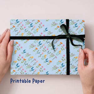 May include: A light blue box with a floral pattern of pink, yellow, and blue flowers, tied with a black velvet ribbon and bow. The words "Printable Paper" are at the bottom.
