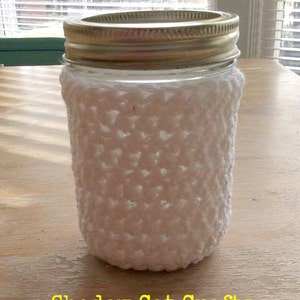 May include: White crocheted jar cozy, a handmade crocheted cover for a glass jar, with the text "Shadow Cat Crafts" at the bottom of the image.