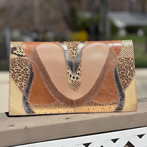 May include: A rectangular clutch with a patchwork design. The clutch features a variety of animal print patterns in shades of brown, tan, and beige. The design includes leopard print, snakeskin, and other textured materials.