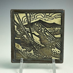 May include: A black and white ceramic tile with a landscape scene. The tile features a stylized mountain range, trees, and water. The tile has a textured surface and a dark brown frame.