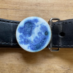 Handmade ceramic full moon adorned disk on hand forged belt buckle