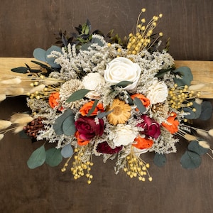 Composizione floreale con arco nuziale autunnale di fiori Sola, fiori secchi arancioni, verdi, bordeaux, erbe, grani, verde di eucalipto conservato