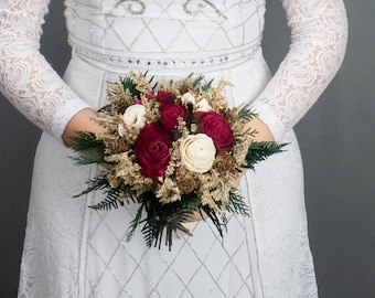 Small winter wedding bridesmaid bridal bouquet with burgundy and ivory sola roses, pine cones, gold dried flowers and preserved greenery