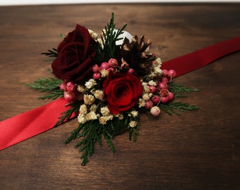 Winter wedding wrist corsage in red white and burgundy, pine cones berries real preserved roses and greenery, woodland wedding