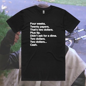 Op de afbeelding: Zwart T-shirt met witte tekst die luidt: "Four weeks, Twenty papers, That's two dollars. Plus tip. Didn't ask for a dime. Two dollars. Two dollars... Cash."