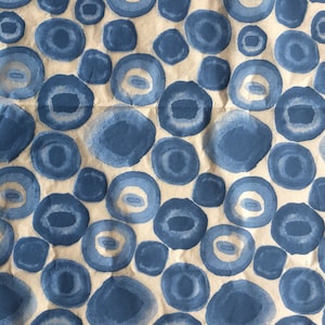 Può includere: Un foglio di carta da pacchi marrone con un motivo ripetitivo di cerchi blu ad acquerello. I cerchi sono di dimensioni diverse e si sovrappongono leggermente.
