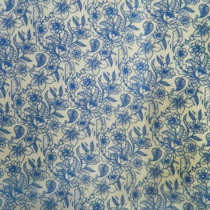 May include: A cream-colored fabric with a blue floral pattern. The pattern features stylized flowers, leaves, and vines.