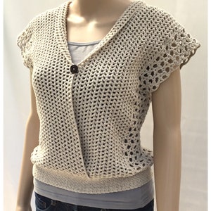 May include: A crocheted cream-colored sleeveless top with a V-neck and a single button closure. The top has a delicate openwork pattern and a slightly fitted silhouette.