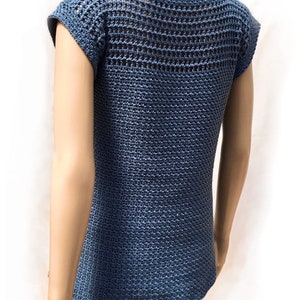 May include: A blue crochet top with a mesh design on the back and short sleeves. The top is shown on a white mannequin.