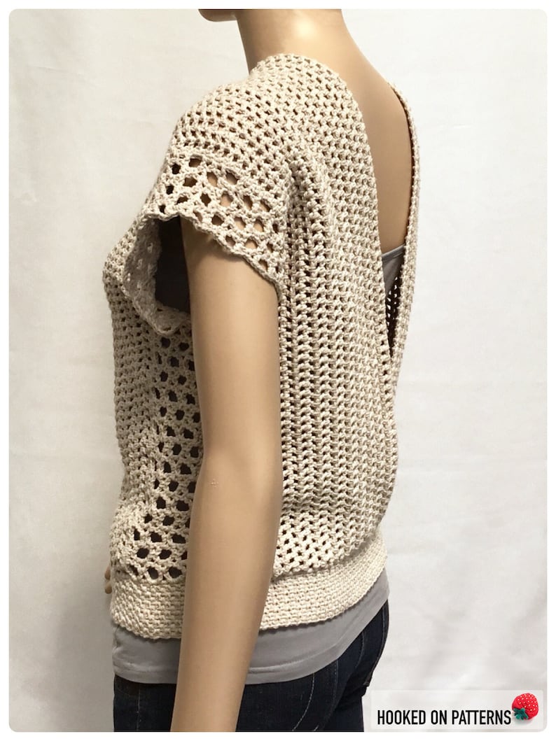 May include: A crocheted top with a low back and short sleeves. The top is made with a beige yarn and has a lacy pattern.