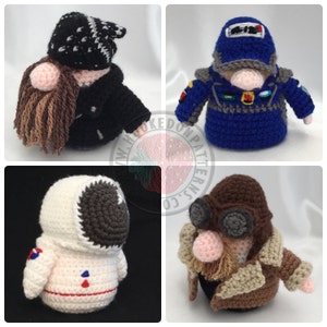 May include: Four crocheted gnomes, each wearing a different costume. The first gnome is wearing a black leather jacket and a black and white bandana. The second gnome is wearing a blue uniform with a silver helmet. The third gnome is wearing a white astronaut suit. The fourth gnome is wearing a brown jacket with goggles and a beard.
