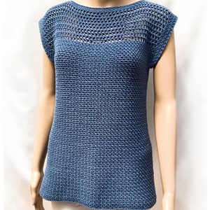 May include: A blue crochet top with a loose fit and short sleeves. The top has a delicate openwork pattern around the neckline.