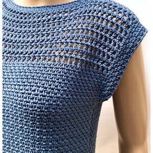 May include: A blue crochet top with a lacy, open-stitch design. The top has a round neckline and short sleeves. The text "HOOKED ON PATTERNS" is visible at the top of the image.