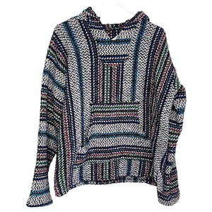 May include: A multi-colored Baja hoodie with a front pocket and hood. The hoodie features a pattern of vertical stripes in blue, white, green, red, and black. The garment is made of a woven fabric and is hanging on a white hanger.
