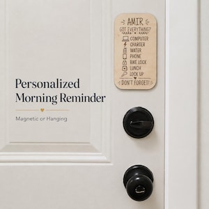 May include: A rectangular light wood sign with rounded corners featuring the engraved text AMIR GOT EVERYTHING? followed by a checklist of icons and words including COMPUTER, CHARGER, WATER, PHONE, BIKE LOCK, LUNCH, LOCK UP, and DON'T FORGET!