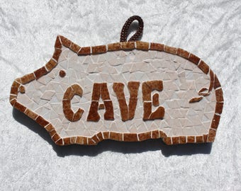 Placa de puerta "cueva" en mosaico en forma de cochinito con la cola en sacacorchos.