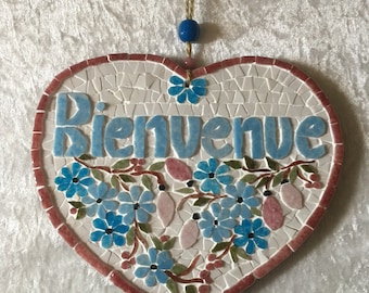 Plaque de porte en mosaïque :" Bienvenue" . Guirlande de fleurettes bleues et roses en relief sur fond blanc. 14cmx17cm avec cordelette .