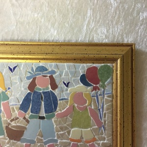 Puede incluir: Una obra de arte de mosaico enmarcada que representa a tres ni&ntilde;os, uno sosteniendo una cesta, otro sosteniendo un globo y el tercero sosteniendo un palo con globos atados. El mosaico est&aacute; hecho de peque&ntilde;os azulejos coloridos.