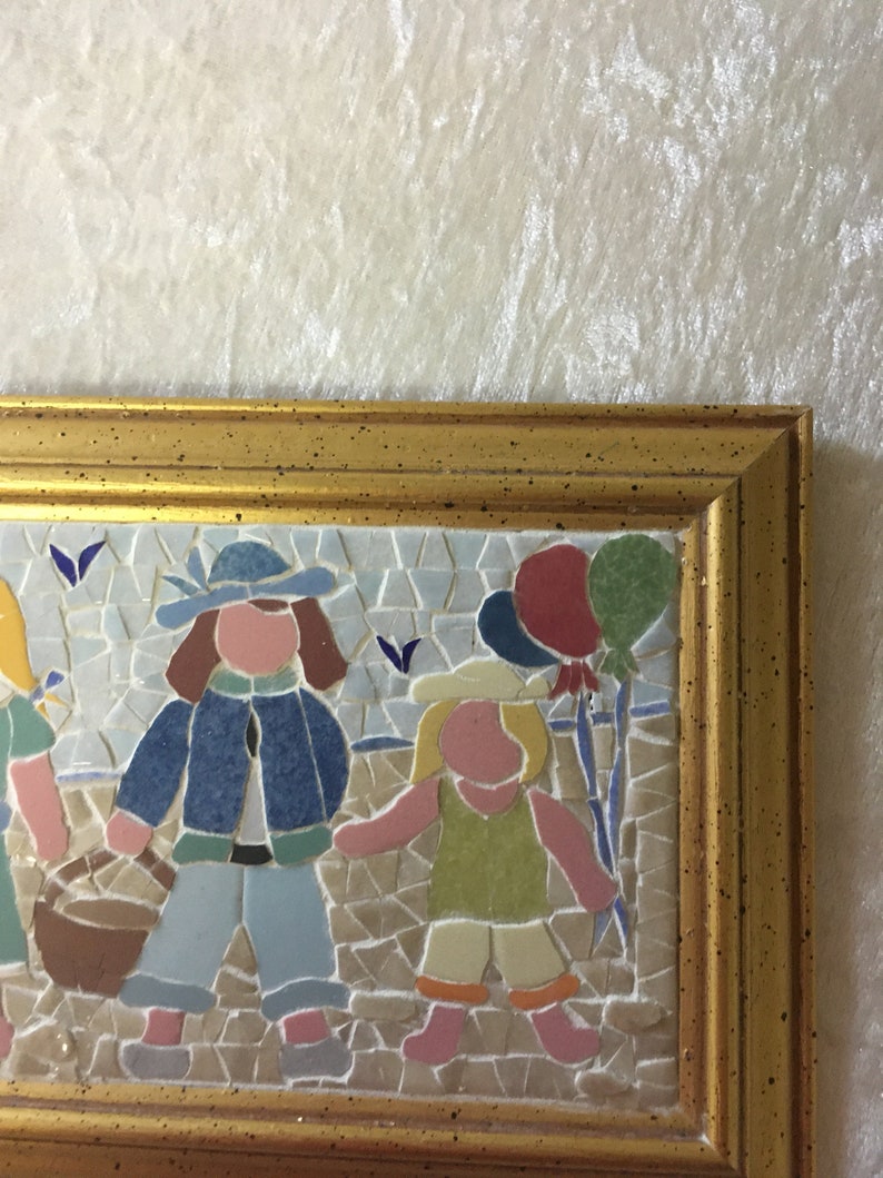 Puede incluir: Una obra de arte de mosaico enmarcada que representa a tres ni&ntilde;os, uno sosteniendo una cesta, otro sosteniendo un globo y el tercero sosteniendo un palo con globos atados. El mosaico est&aacute; hecho de peque&ntilde;os azulejos coloridos.