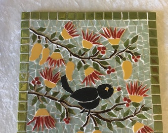 Dessous de plat en mosaïque: Merle chantant dans un mèli mèlo de branches et de fleurs bicolores. 15cmx15cm sur carreau de faïence.