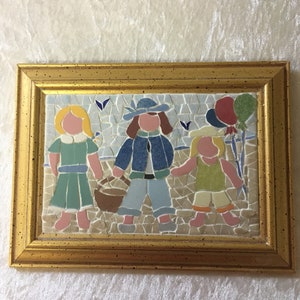Puede incluir: Una obra de arte de mosaico enmarcada que representa a tres ni&ntilde;os, dos ni&ntilde;as y un ni&ntilde;o, caminando juntos. La ni&ntilde;a de la izquierda lleva un vestido azul y verde, el ni&ntilde;o del medio lleva una chaqueta azul y pantalones vaqueros, y la ni&ntilde;a de la derecha lleva un vestido amarillo y verde. Todos llevan una cesta y globos.